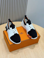 Sneaker bianche con dettagli arancioni e scatola di design elegante su tavolo in legno.
