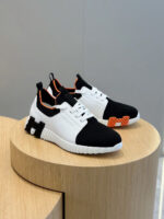 Scarpe sportive moderne con dettagli arancioni e design trendy su piattaforma di legno