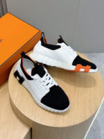 Sneakers moderne nero e bianco con dettagli arancioni, su piedistallo in legno, stile e comfort garantiti.