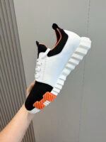Sneaker moderna bianca e nera con dettagli arancioni, stile casual e comfort perfetto.