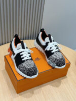 Sneakers moderne nere e bianche con dettagli arancioni su elegante scatola arancione.