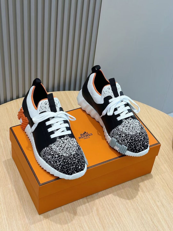Sneakers moderne nere e bianche con dettagli arancioni su elegante scatola arancione.