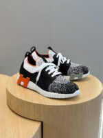 Sneakers moderne con dettagli speckled, accenti arancioni e design innovativo su pedale di legno.