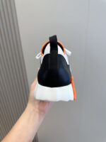 Sneaker nera sportiva con dettagli arancioni e bianco, comfort e stile moderno per ogni attività.
