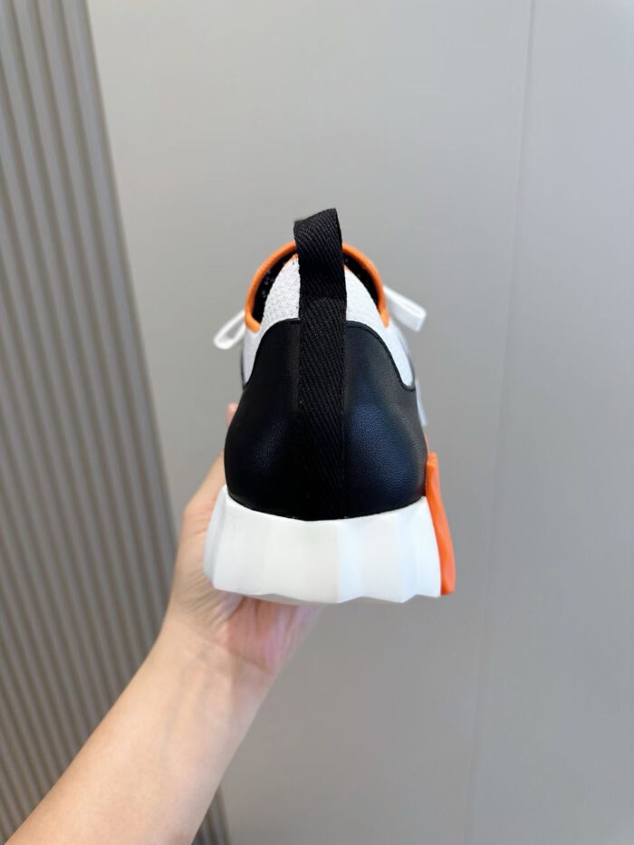 Sneaker nera sportiva con dettagli arancioni e bianco, comfort e stile moderno per ogni attività.