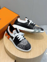 Sneakers moderne con dettagli in nero, bianco e arancione su supporto di legno.