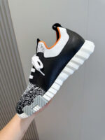 Sneaker sportiva moderna con design colorato, suola chunky e dettagli eleganti in nero, bianco e arancione.