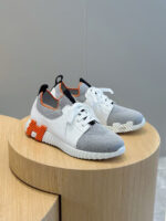 Sneakers sportive bianche con dettagli arancioni, design moderno e su piattaforma in legno.