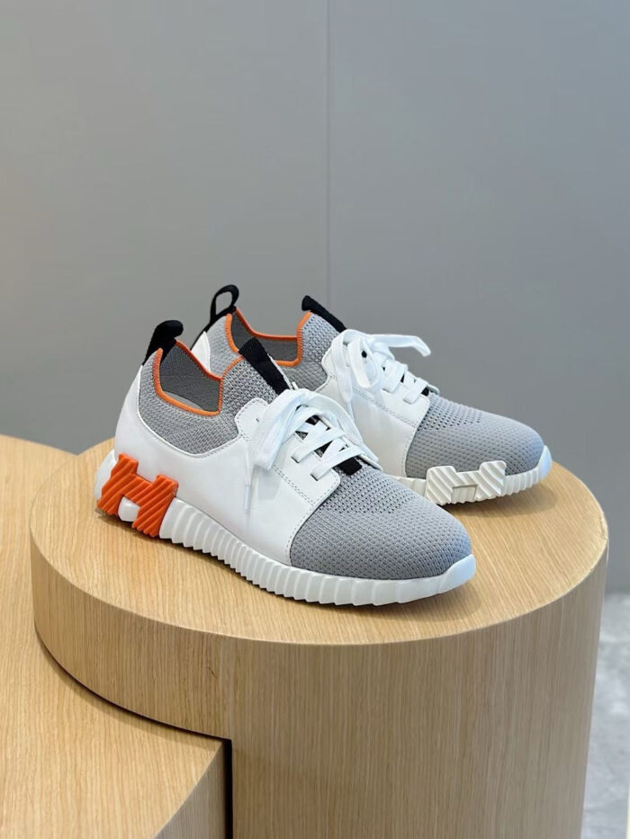 Sneakers sportive bianche con dettagli arancioni, design moderno e su piattaforma in legno.