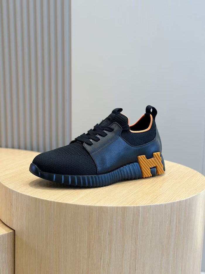 Sneaker sportiva nera con logo H in tonalità contrastante e dettagli arancioni eleganti.
