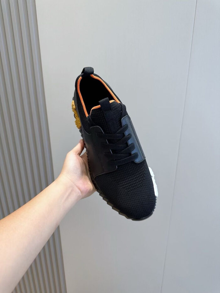 Sneaker nera moderna con dettagli arancione e suola antiscivolo, leggera e sportiva.