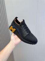 Scarpa sneakers nera con interni arancioni, suola robusta e dettaglio giallo sul heel.