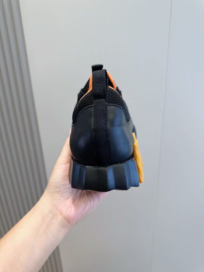 Sneaker nera con dettagli gialli e arancioni, stile sportivo e moderno, per ogni attività.