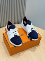 Sneakers navy blu con dettagli arancioni su scatola vibrante, stile sportivo e moderno.