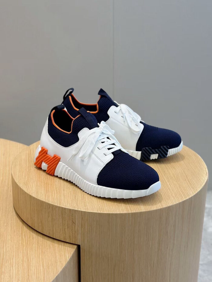 Sneakers moderne blu, bianco e arancione su pedana in legno, stile casual e sportivo.