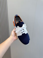 Sneaker moderna navy e bianco con dettagli arancioni, stile sportivo e comfort casuale.
