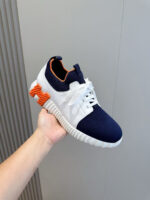 Sneaker moderna blu navy e bianca con dettaglio arancione, stile sportivo e design trendy.