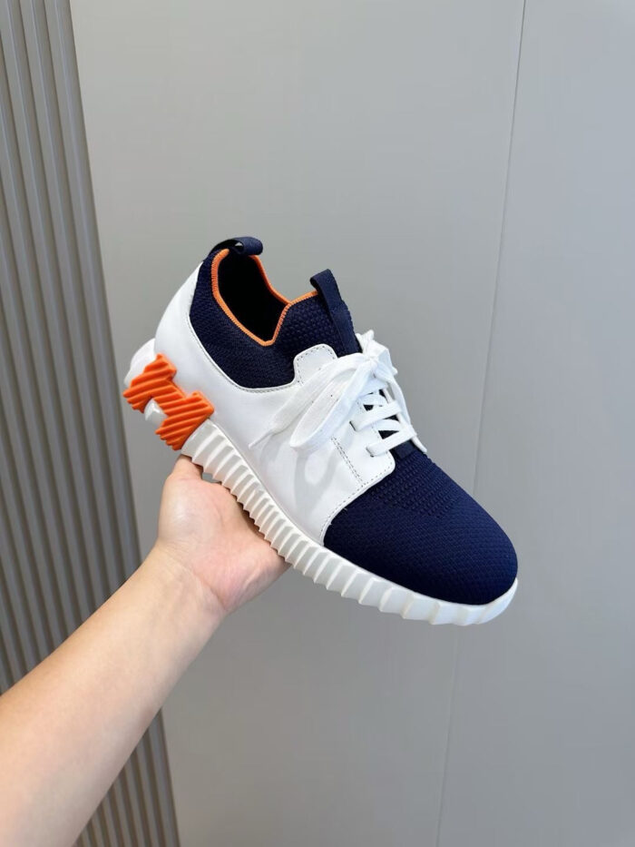 Sneaker moderna blu navy e bianca con dettaglio arancione, stile sportivo e design trendy.