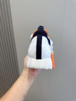 Sneaker moderna bianca con dettagli arancioni e blu navy, supporto e comfort elevati.