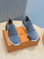 Scarpe da ginnastica moderne grigie e arancioni su base in legno bianco.
