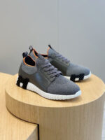 Sneakers grigi moderni con dettagli arancioni e suola spessa, ideali per stile e comfort.