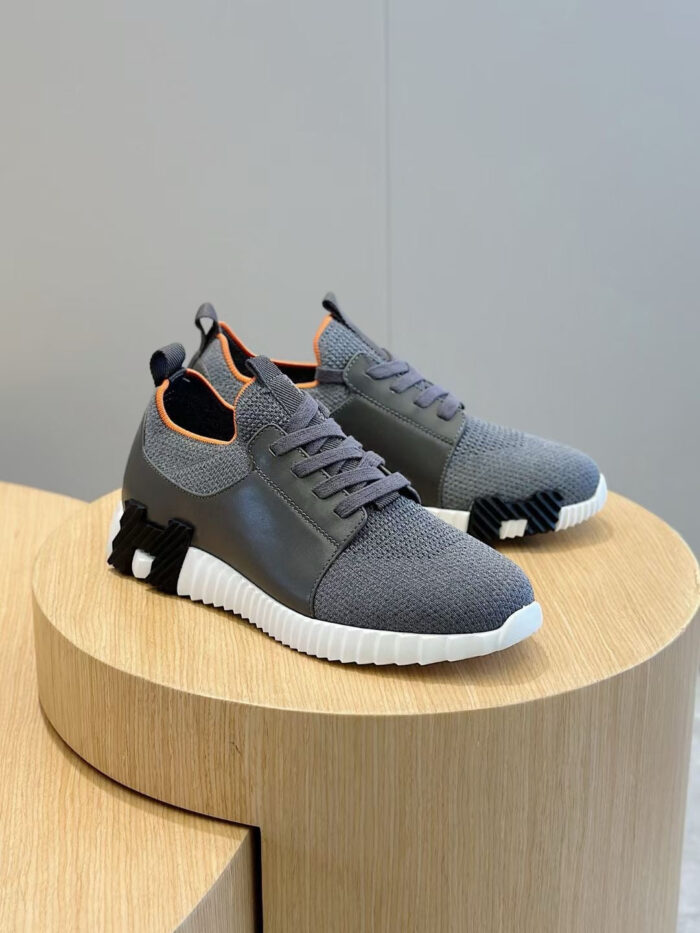 Sneakers grigi moderni con dettagli arancioni e suola spessa, ideali per stile e comfort.
