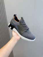 Scarpe sportive grigie con dettagli arancioni, comode, leggere e dal design moderno.
