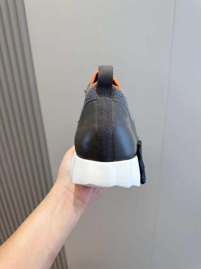 Sneaker moderna con suola spessa, dettagli arancioni e design elegante in mesh e pelle lucida.