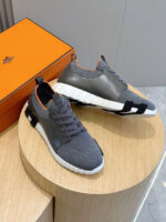 Sneakers grigie con dettagli arancioni, supporto comfort e box moderno, stile sportivo e casual.