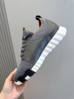 Sneaker moderna grigia con dettagli arancioni e suola antiscivolo, design elegante e confortevole.