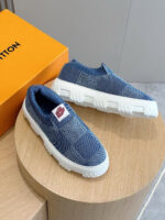 Sneakers slip-on blu con suola chunky e scatola arancione, stile moderno e sportivo.
