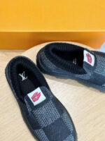 Scarpe slip-on di lusso con motivo quadrettato, logo a contrasto e confezione arancione elegante.
