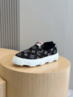 Sneaker slip-on Louis Vuitton Monogram nera e bianca su supporto in legno, stile casual e di lusso