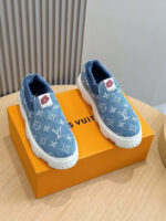 Scarpe slip-on Louis Vuitton in denim blu con suola bianca, su scatola arancione brillante.