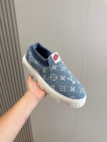 Sneaker denim blu con motivi luxury, sole bianca robusta e dettaglio rosso sul linguetta.