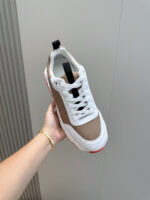 Sneaker moderna bianca e marrone con dettagli neri e suola rossa per stile casual e sporty.