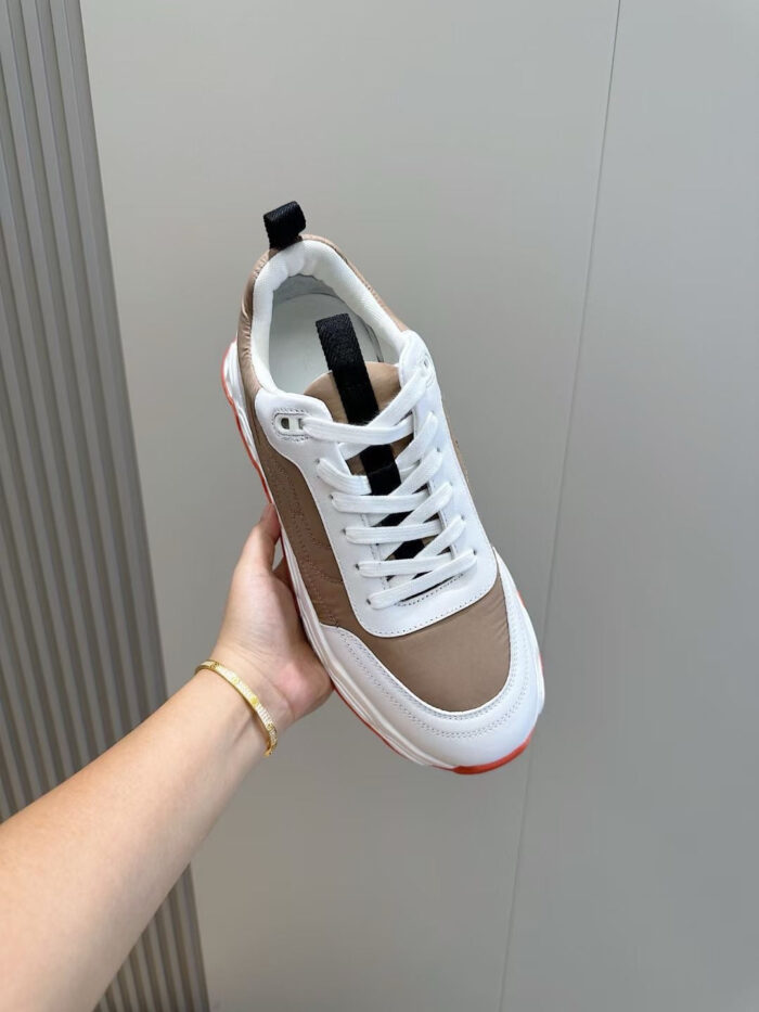 Sneaker moderna bianca e marrone con dettagli neri e suola rossa per stile casual e sporty.