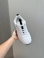 Sneaker bianca minimalista tenuta a mano, stile casual e moderno, su sfondo neutro.