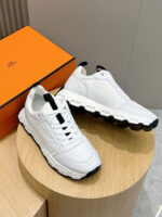 Sneaker bianca di lusso con suola nera, eleganti su tavolo in legno, stile urbano e moderno.