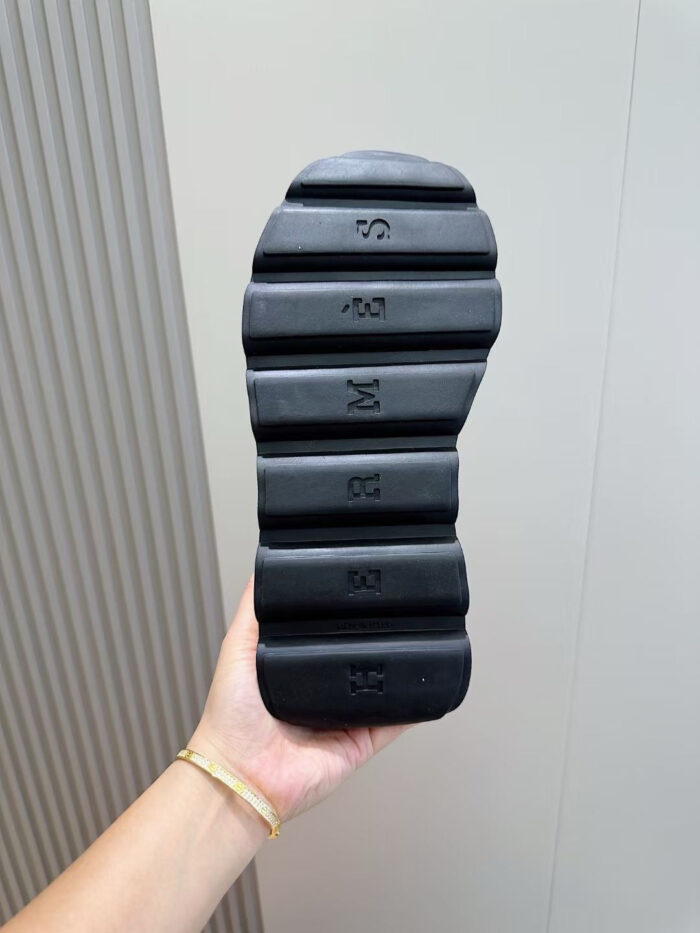 Sole di scarpa con design multilayer e dettagli embossati, mostrato da una mano.