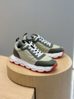 Sneakers moderne verde e crema con suola a contrasto su supporto in legno.