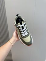 Sneaker moderna verde oliva con suola comfort, dettagli color arancio e design sportivo-elegante.