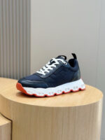 Sneaker sportiva navy con suola arancione su supporto in legno, stile moderno e versatile.