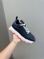 Scarpa sportiva navy con dettagli arancio, suola spumosa e design moderno perfetto per l’attività.
