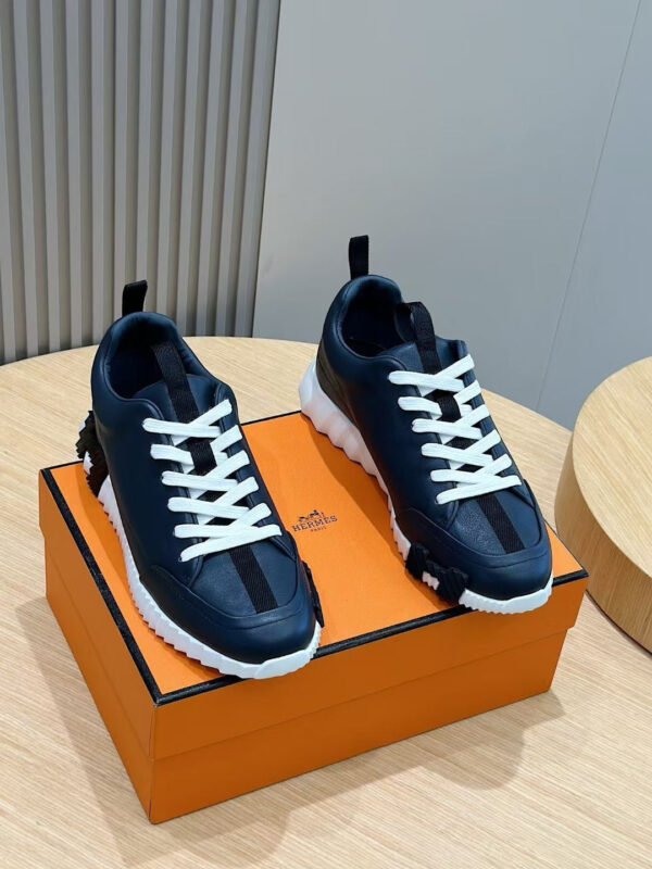 Scarpe da ginnastica navy su scatola arancione di lusso, stile sportivo ed elegante.