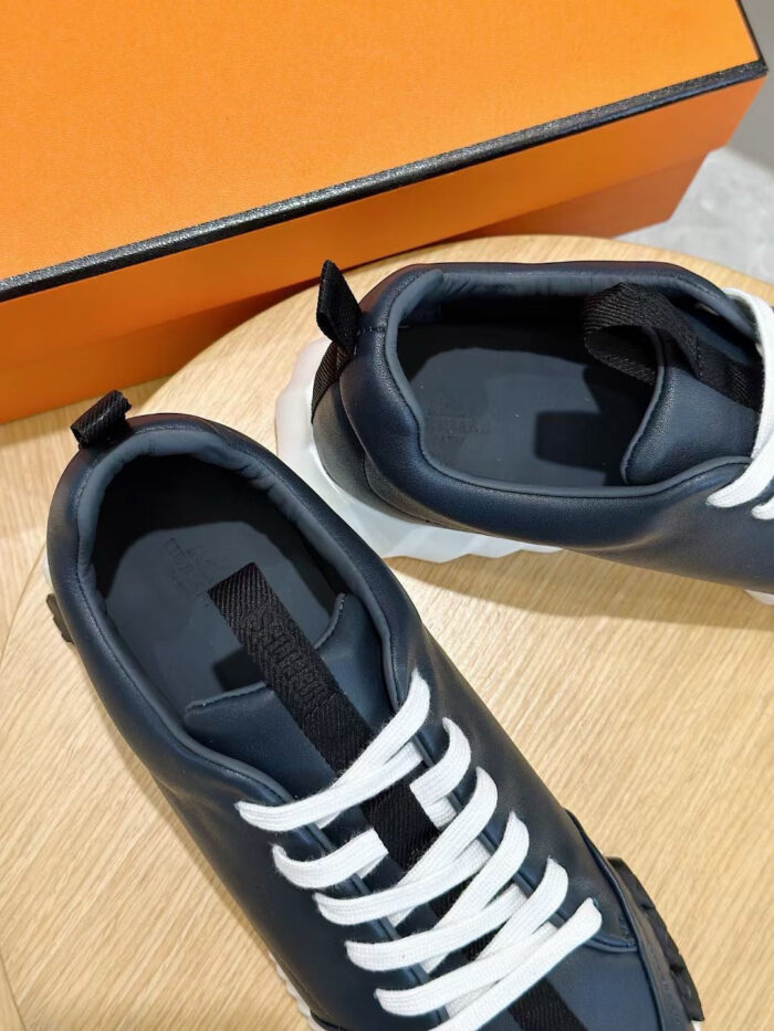 Scarpe da moda navy con lacci bianchi, elegante packaging oro e design moderno.