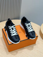 Scarpe sportive nere con suola bianca su scatola arancione, stile moderno e casual.