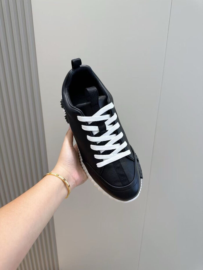 Sneaker nera moderna con suola bianca, stile minimalista e versatile, in primo piano.