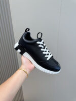 Sneaker nera moderna con lacci bianchi e suola spessa, stile casual e sportivo elegante.