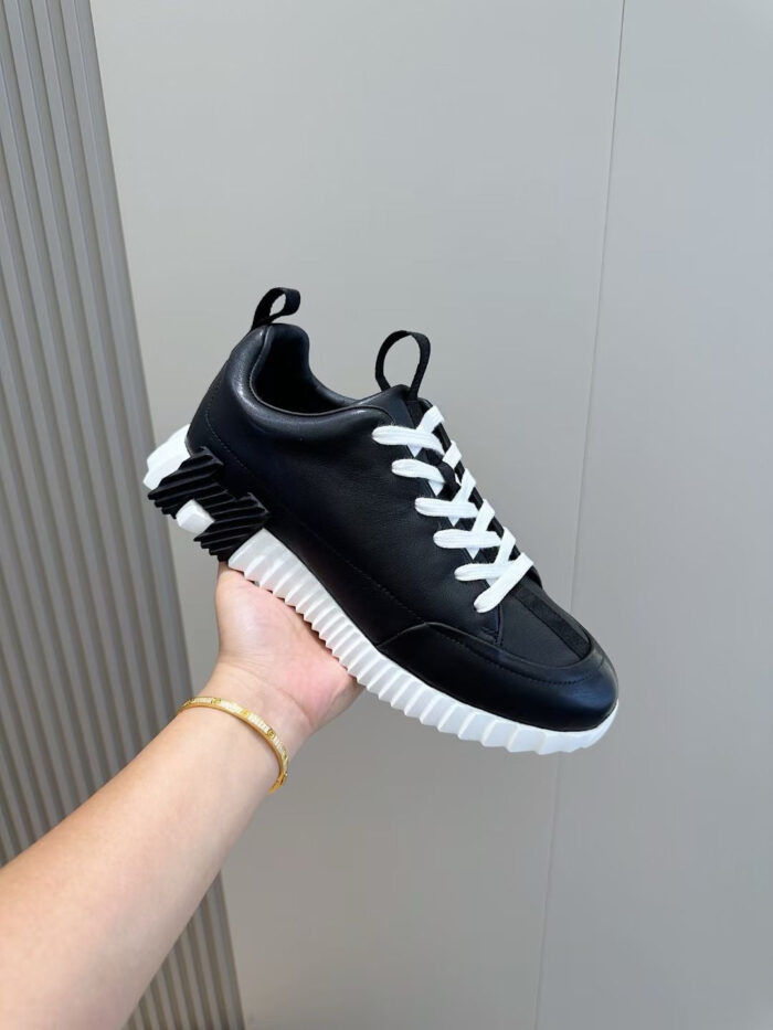 Sneaker nera moderna con lacci bianchi e suola spessa, stile casual e sportivo elegante.
